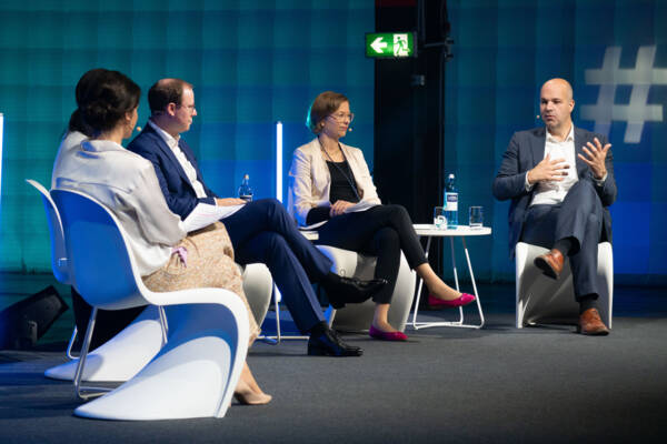 Das Bild zeigt alle Teilnehmenden der Paneldiskussion auf der Bühne. Folgende Expert*innen sind zu sehen (von links nach rechts): Isabell Körner (Moderation); Dr. Feiyu Xu, KI-Expertin; Marc Böttger, Geschäftsführer, profine GmbH; Dr. Karoline Kampermann, Abteilungsleiterin Wirtschaftspolitik, Außenwirtschaft, Mittelstand & Steuern, VDA e.V und Prof. Marcel Fratzscher, Ph.D., Präsident des Deutschen Instituts für Wirtschaftsforschung.